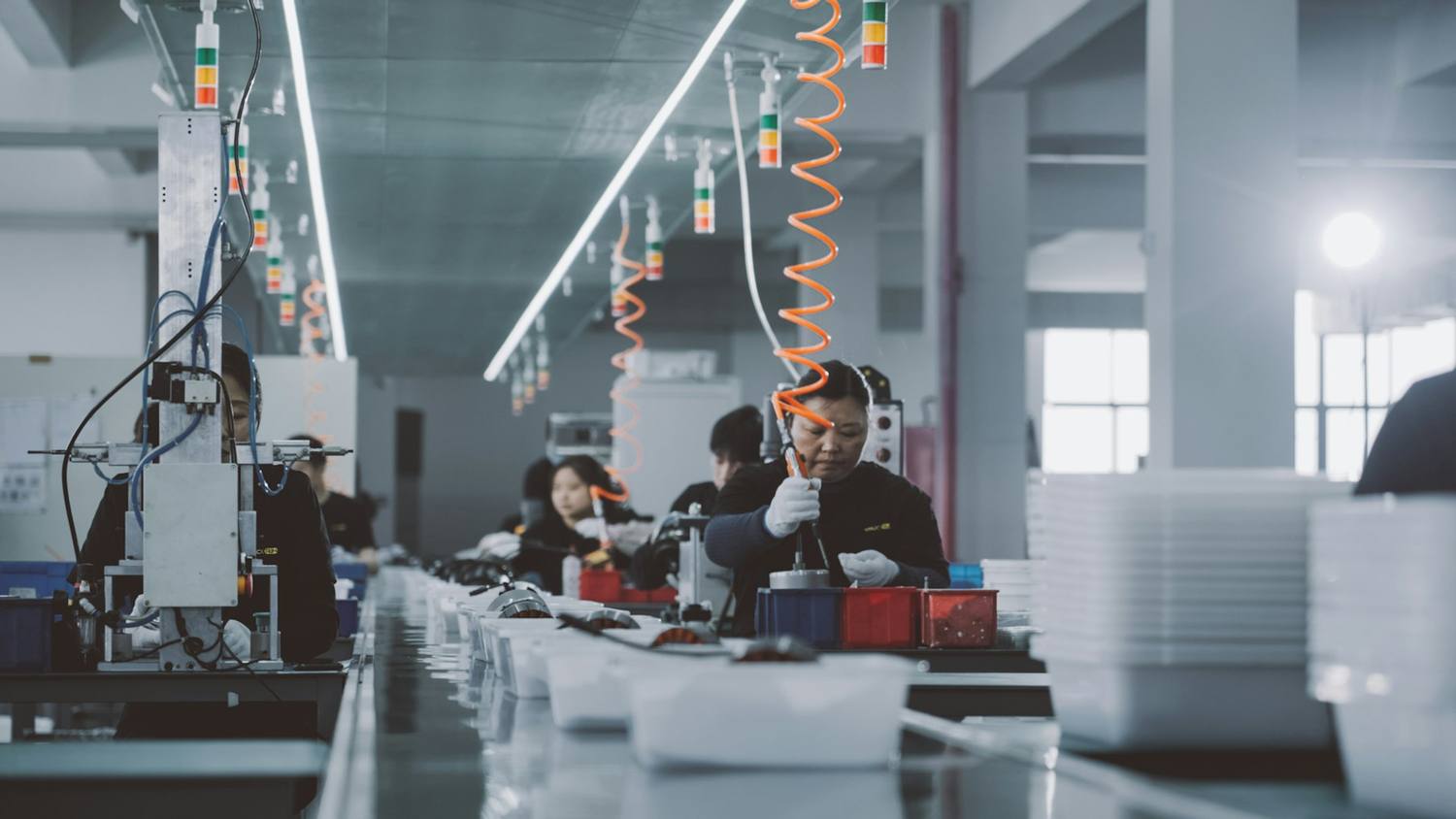 Operators working along an electro-mechanical assembly line on the production floor